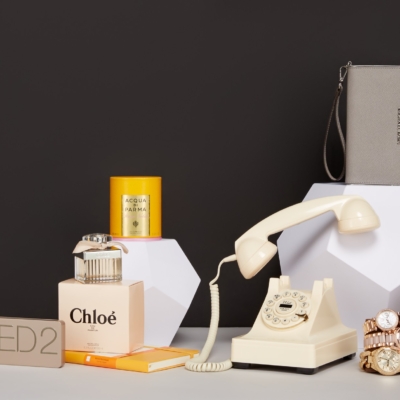 Collection of stylish accessories like Urban Decay eye shadow palette, vintage telephone, Michel Kors purse, Chloe perfume and gold watches
